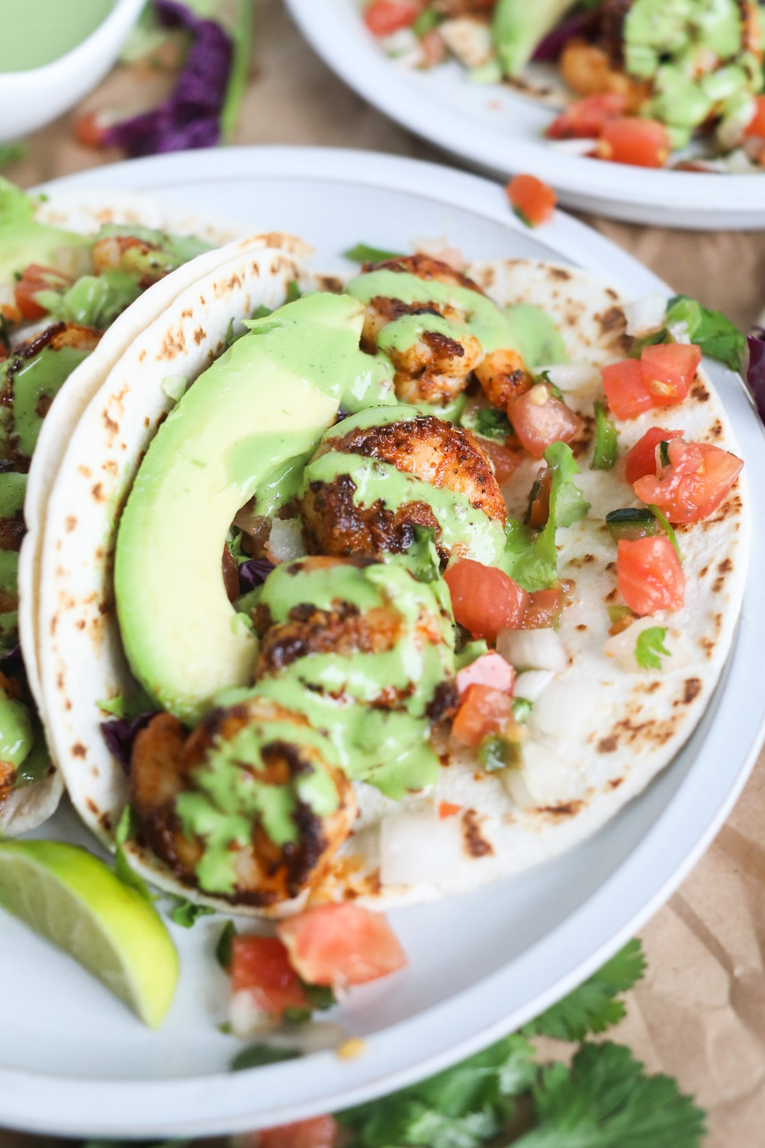 Tacos with blackened shrimp with cilantro lime drizzle with pico de gallo, sliced avocado and lime slice.