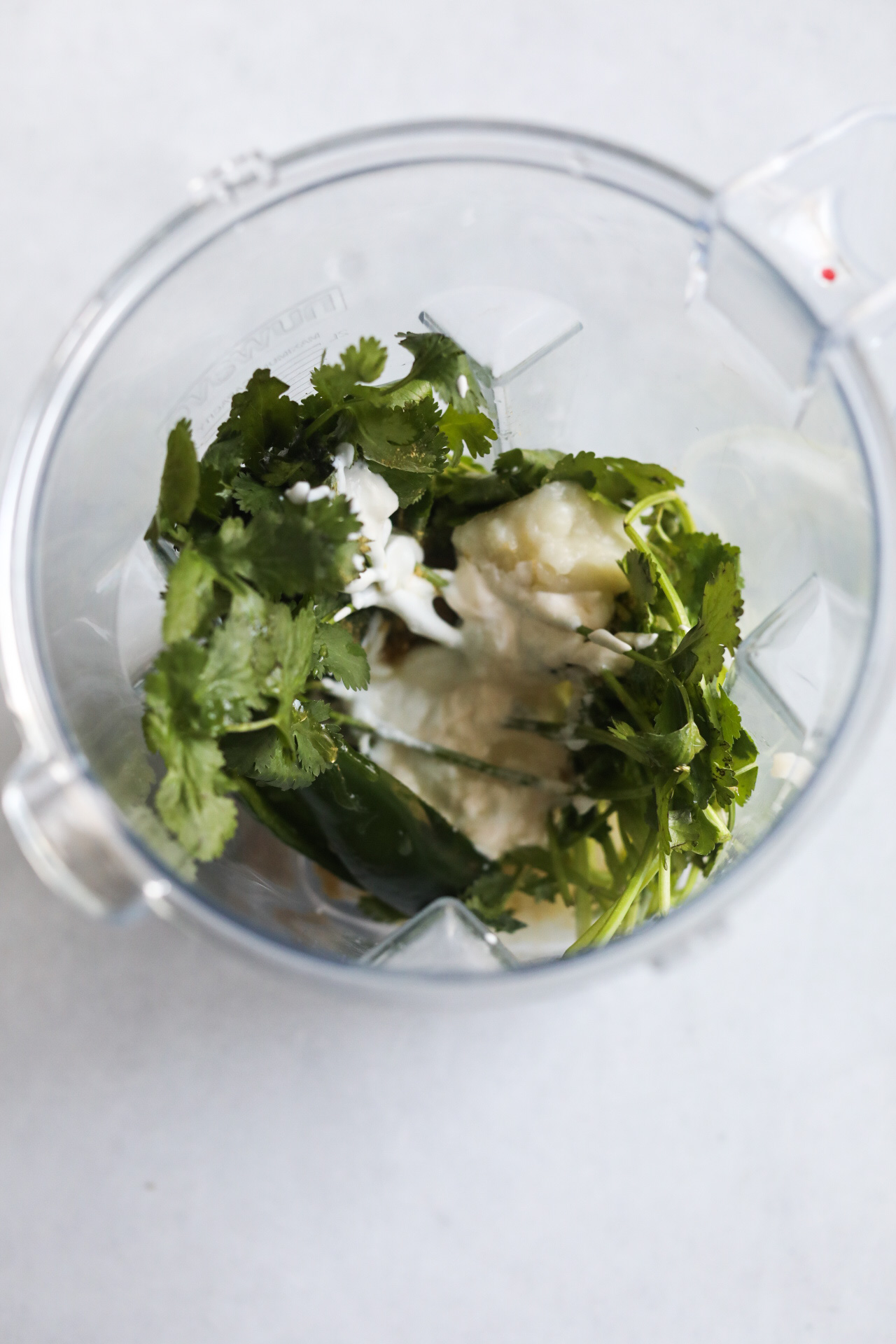 Cilantro lime sauce ingredients in a blender before being blended, top down image.