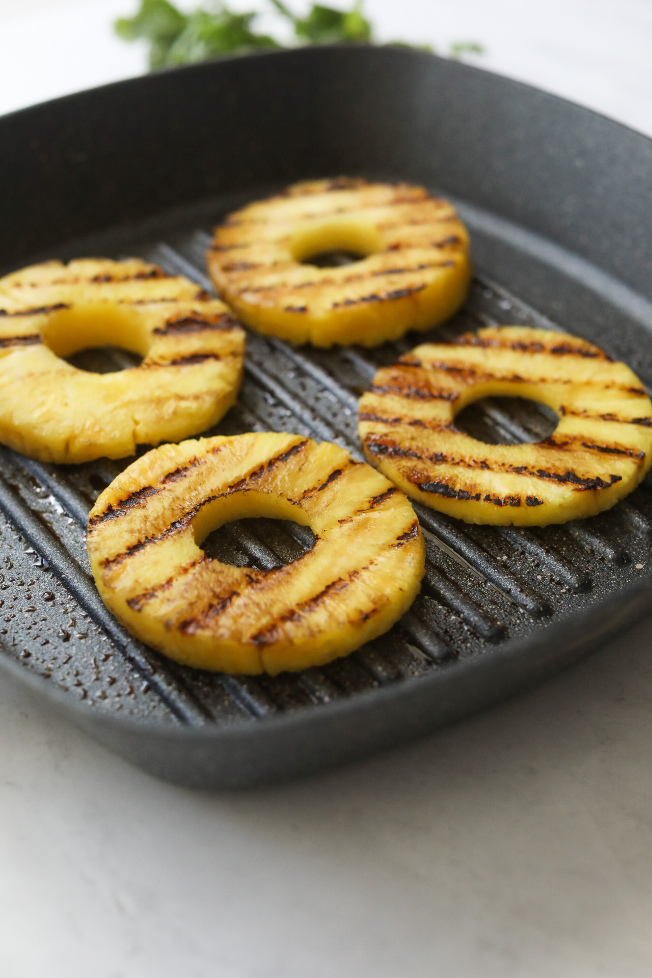 Grilled pineapple slices with grill marks in pan. 