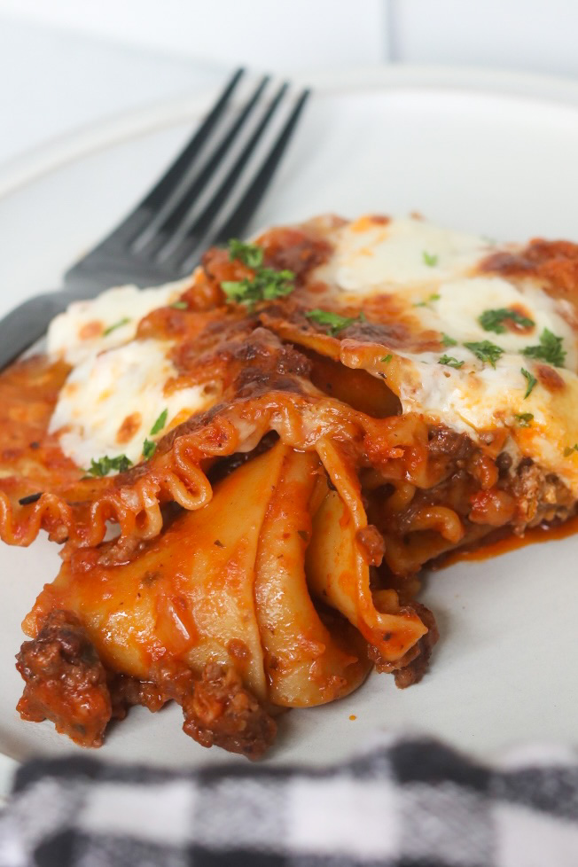 Plated one pot skillet lasagna served on a matte gray plate topped with fresh parsley and a black fork.