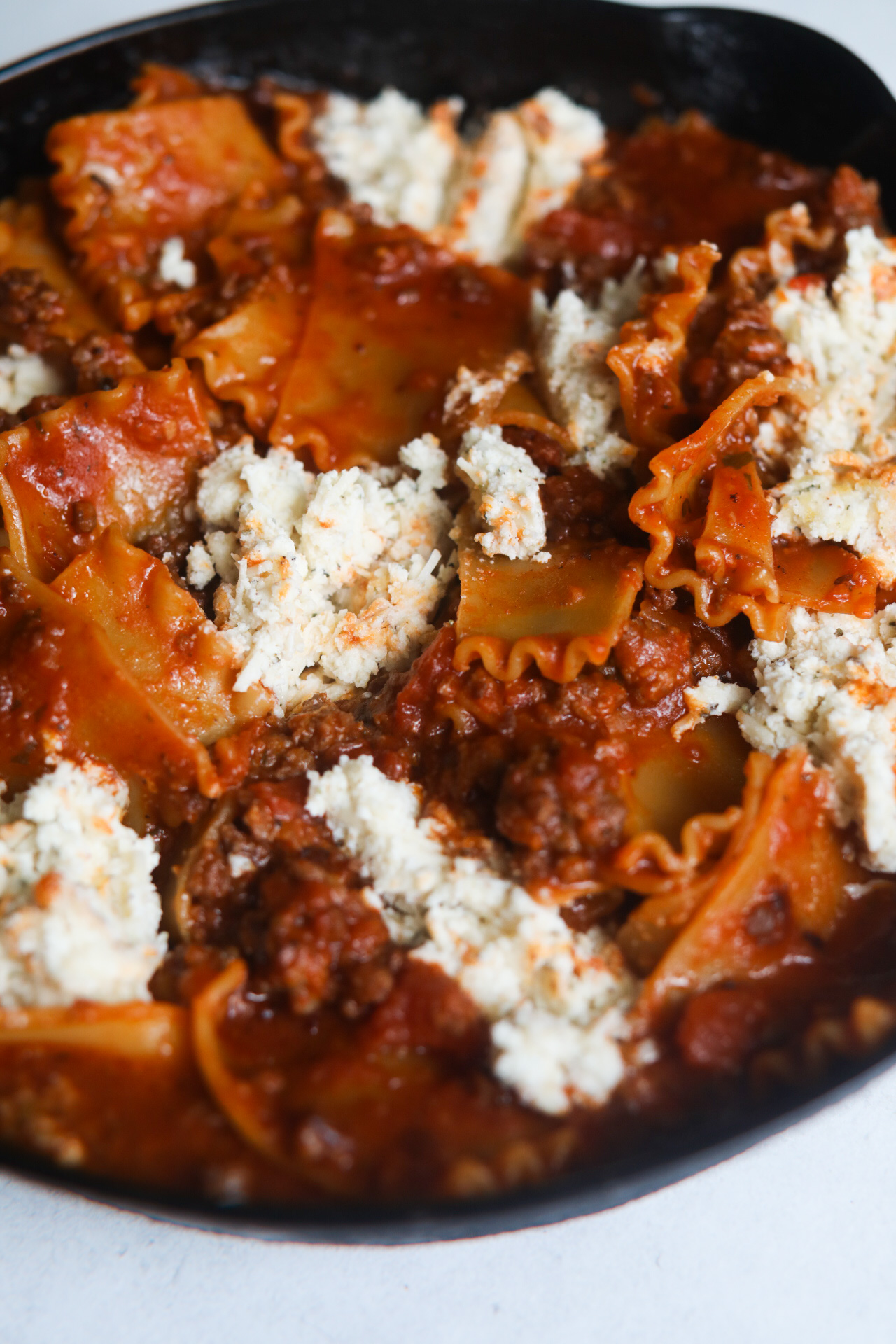 Image of process shot with unbaked lasagna with pasta, noodles, sauce and ricotta cheese mixture.