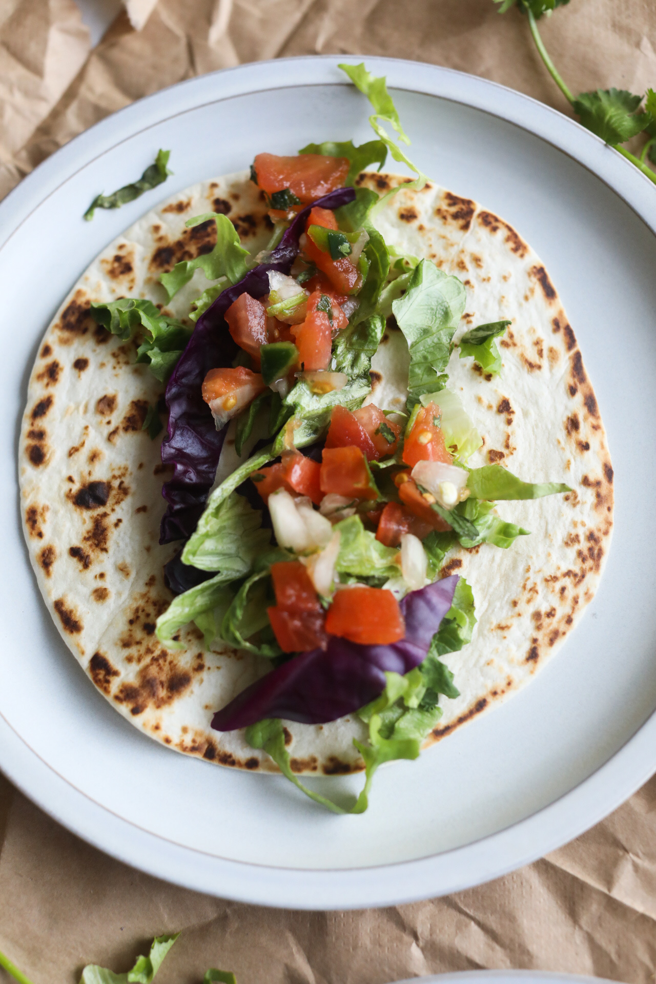 Process shot with tortilla, lettuce and cabbage on a gray matte plate.