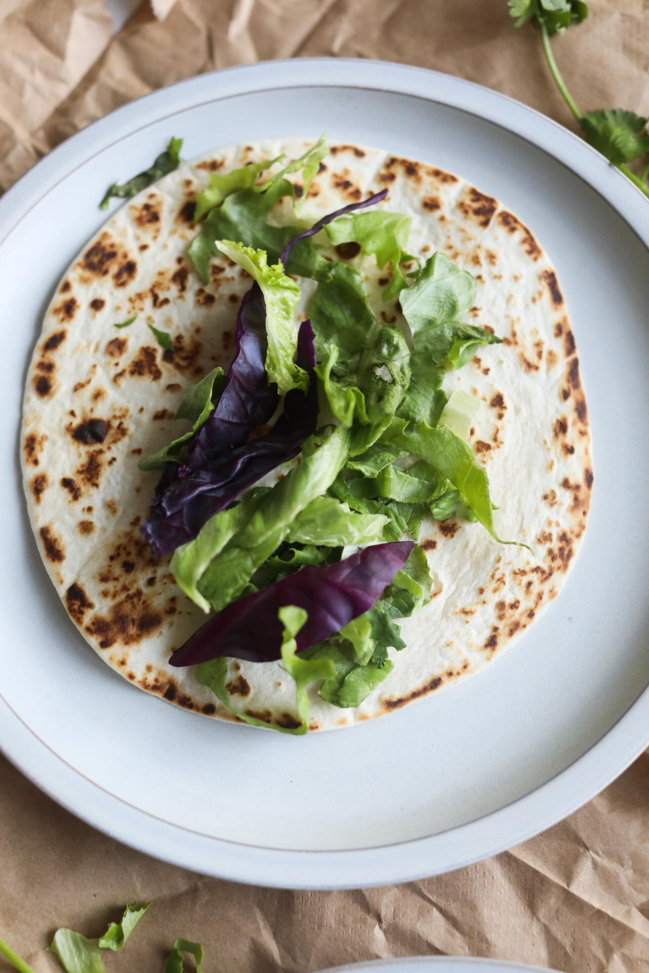 Gray matte plate with tortilla, shredded lettuce and cabbage.