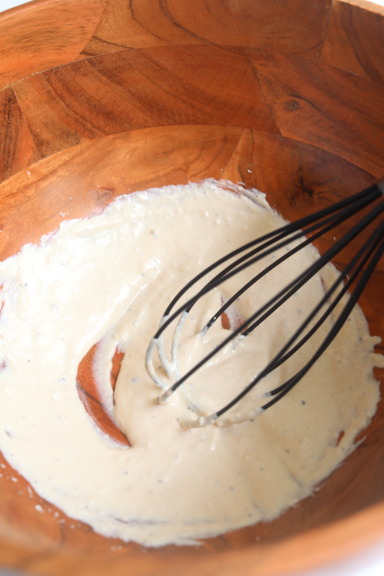 Caesar dressing in bowl with whisk.