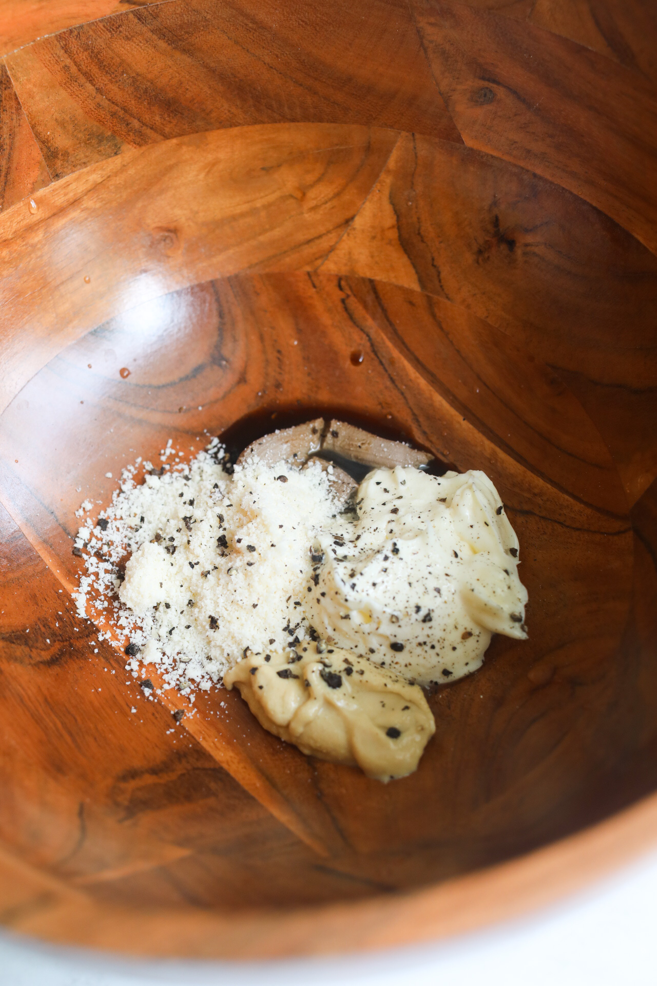 Salad dressing in a wooden bowl before being mixed for Caesar Salad.