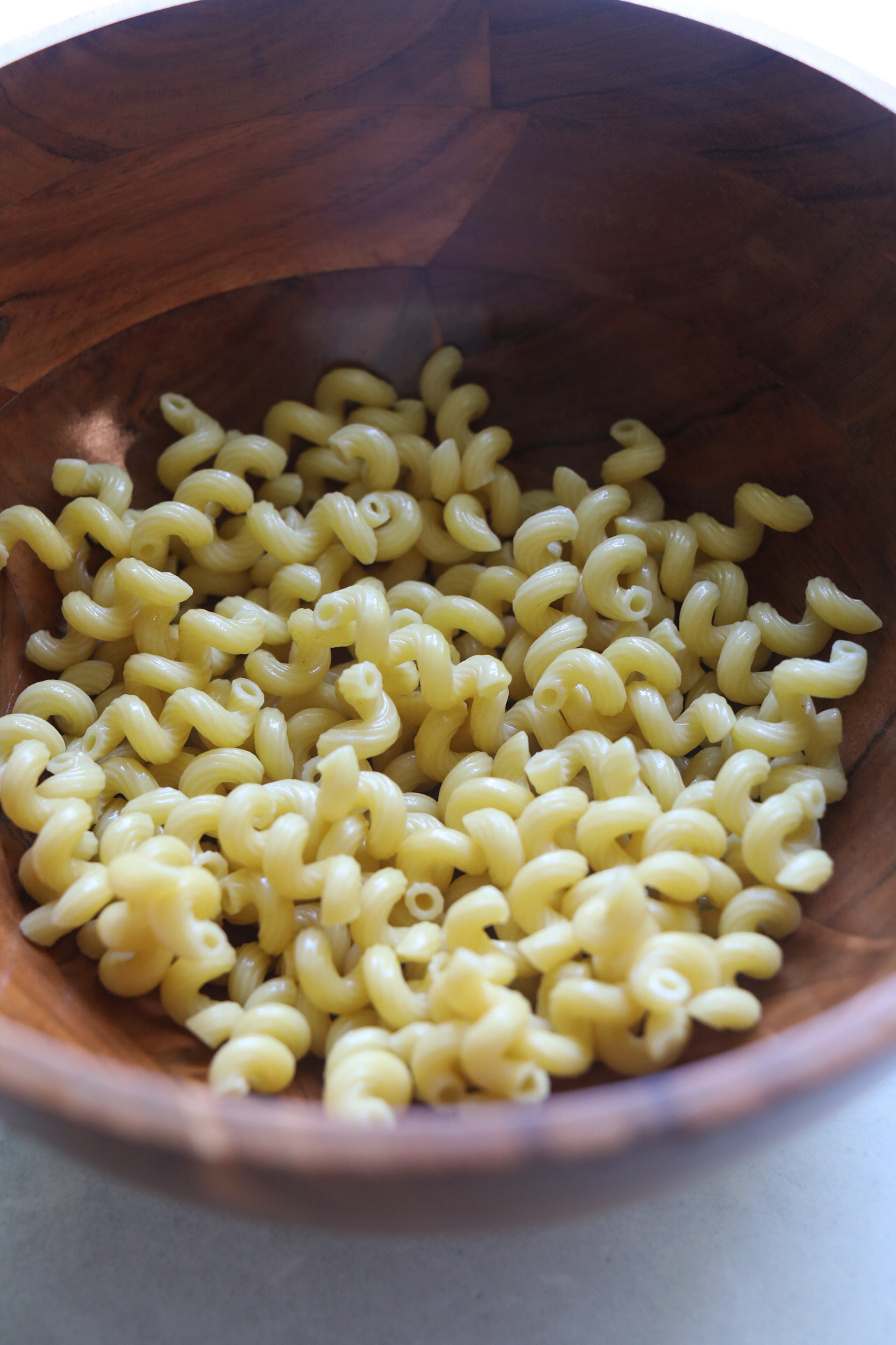 Cooked spiral pasta in wooden bowl. 
