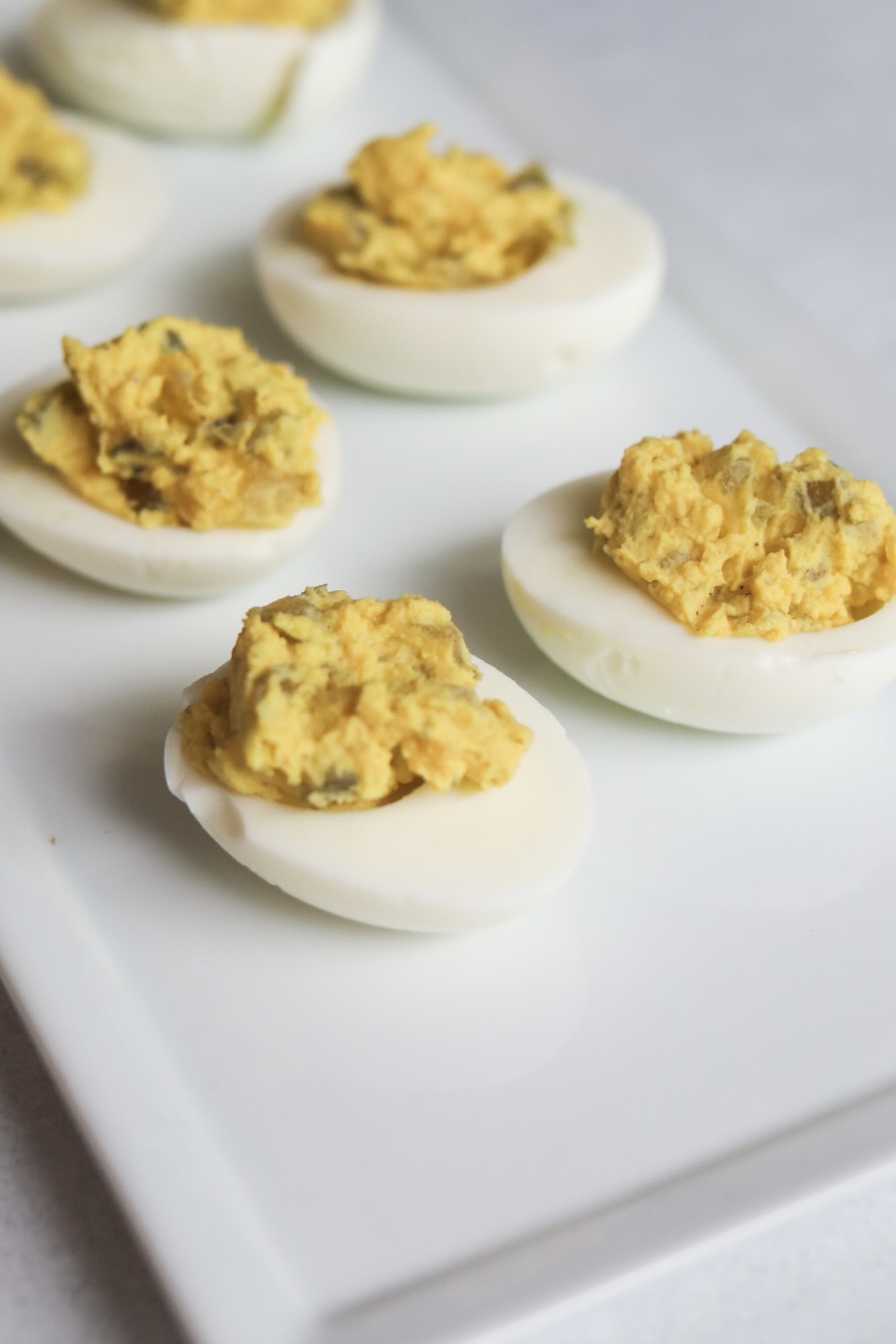 Deviled eggs with filling on a white plate. 