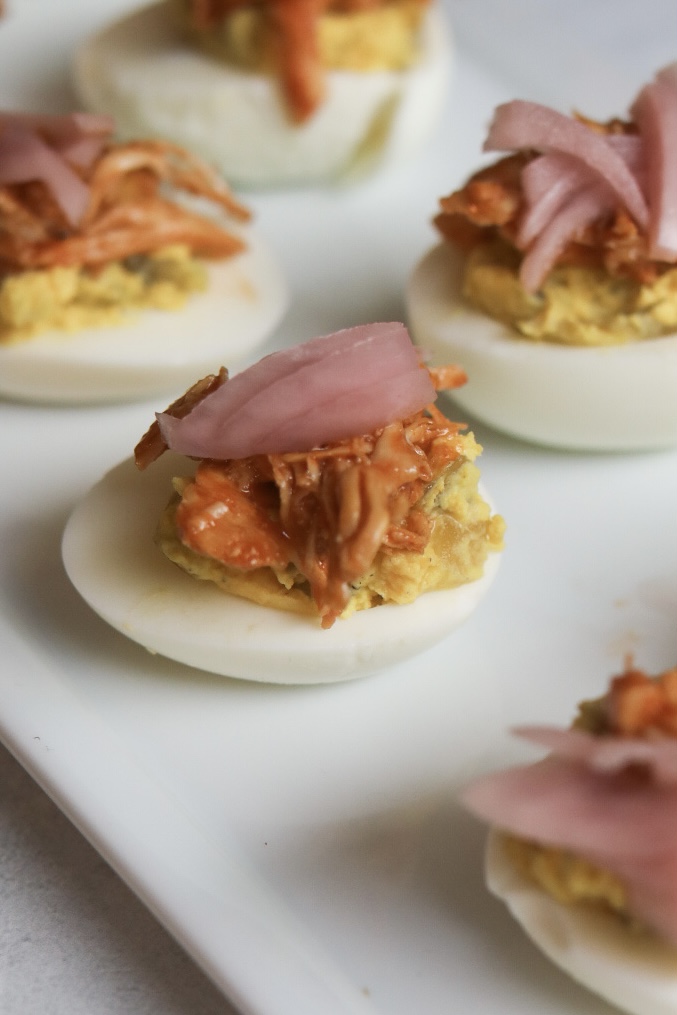 Loaded deviled eggs topped with shredded BBQ chicken and pickled red onion. 