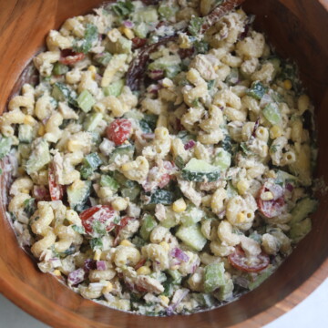 Tuna pasta salad stirred in wooden bowl with wooden spoon.