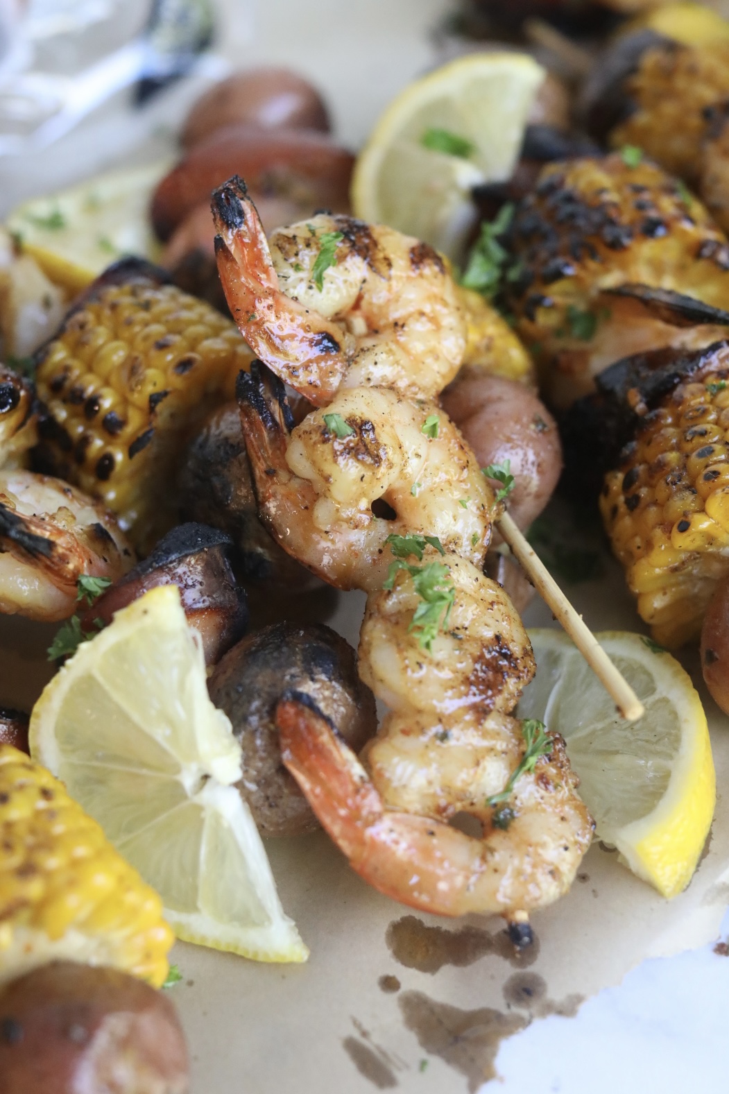 Final recipe images of grilled shrimp kabobs. Shrimp kabobs have charred finishes and garnished with fresh lemon slices and parsley