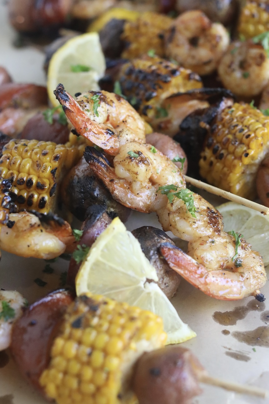 Final recipe images of grilled shrimp kabobs. Shrimp kabobs have charred finishes and garnished with fresh lemon slices and parsley