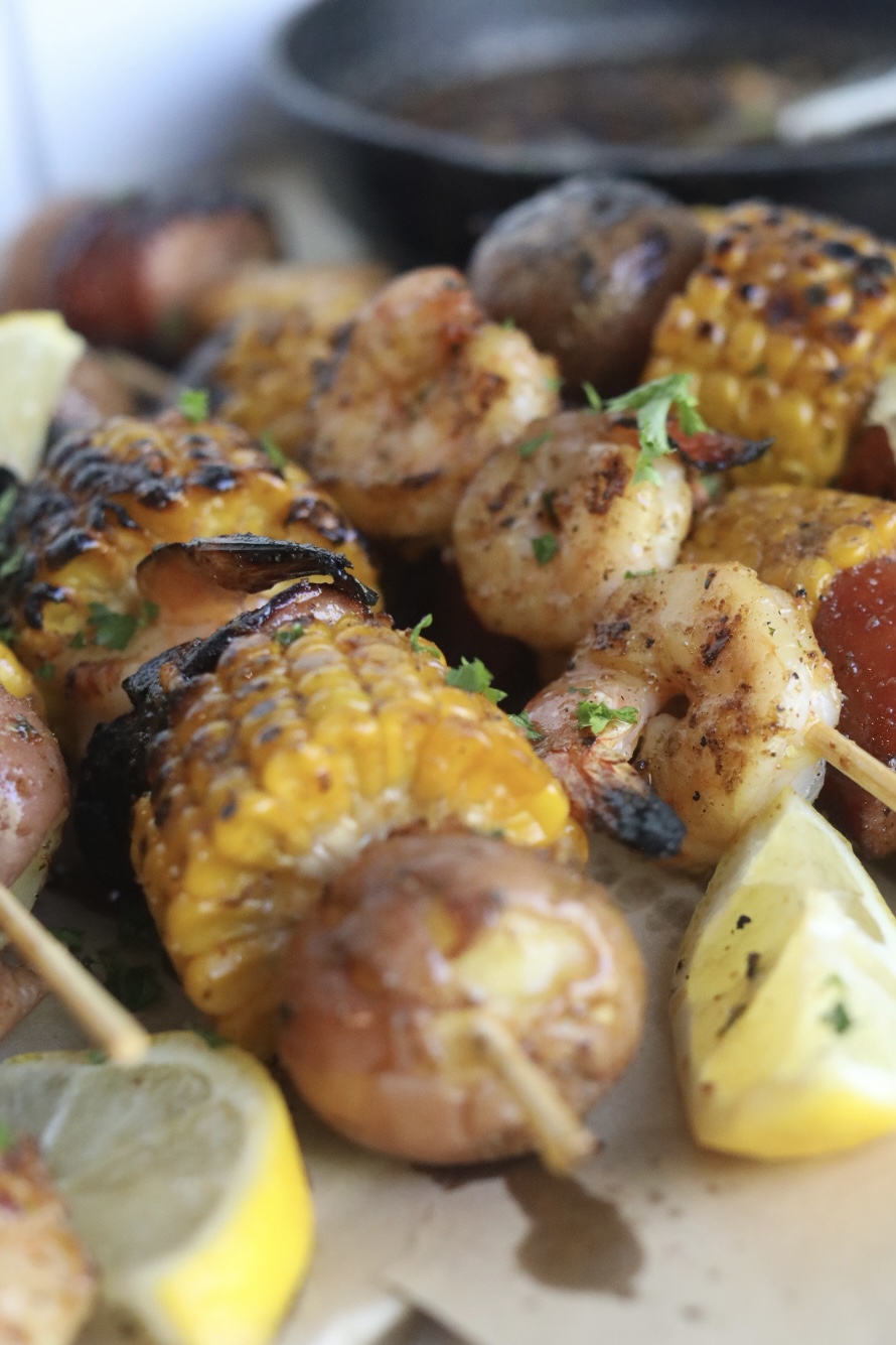 Final recipe images of grilled shrimp kabobs. Shrimp kabobs have charred finishes and garnished with fresh lemon slices and parsley