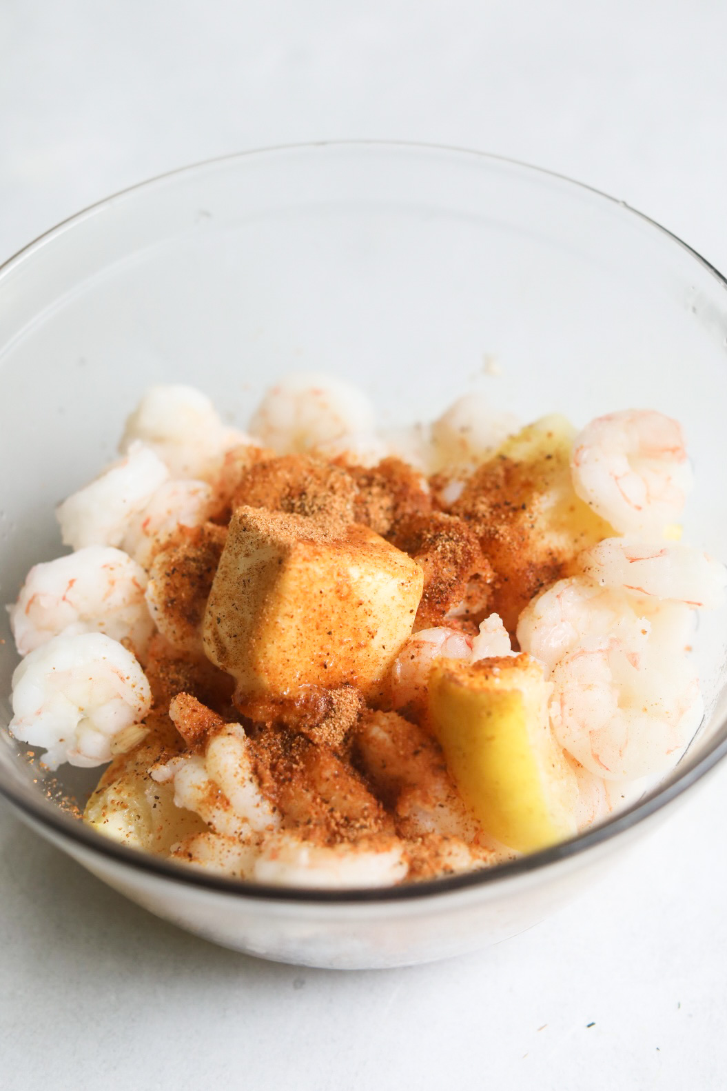 Poached shrimp in bowl with butter unmixed.