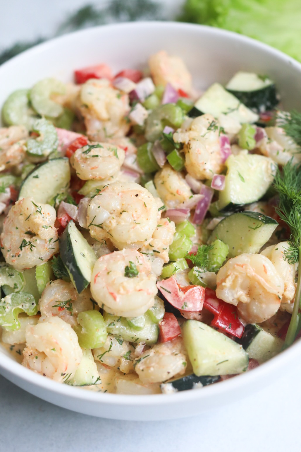 Final recipe of cold shrimp salad plated in a white bowl with fresh dill.