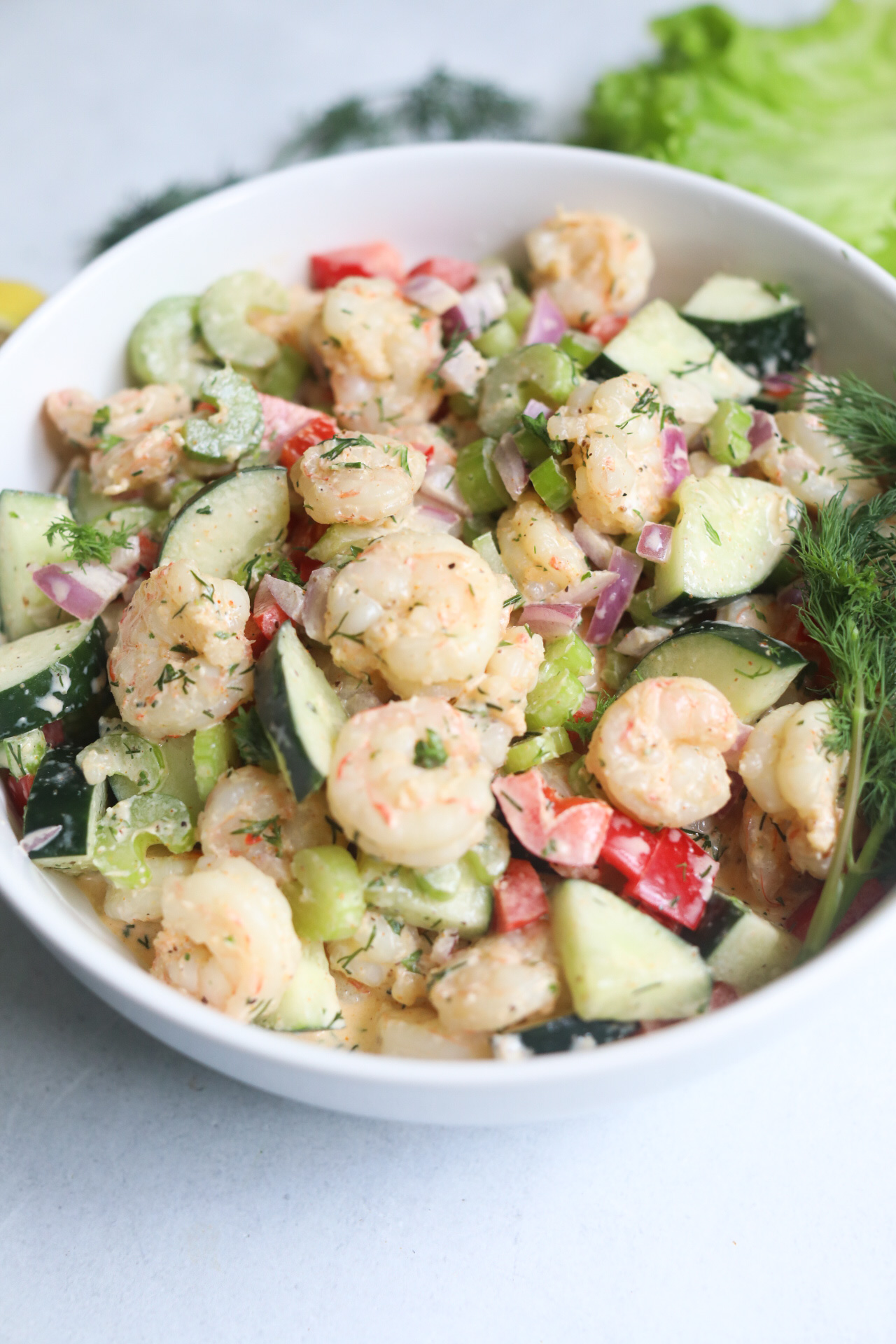 Final recipe of cold shrimp salad plated in a white bowl with fresh dill.