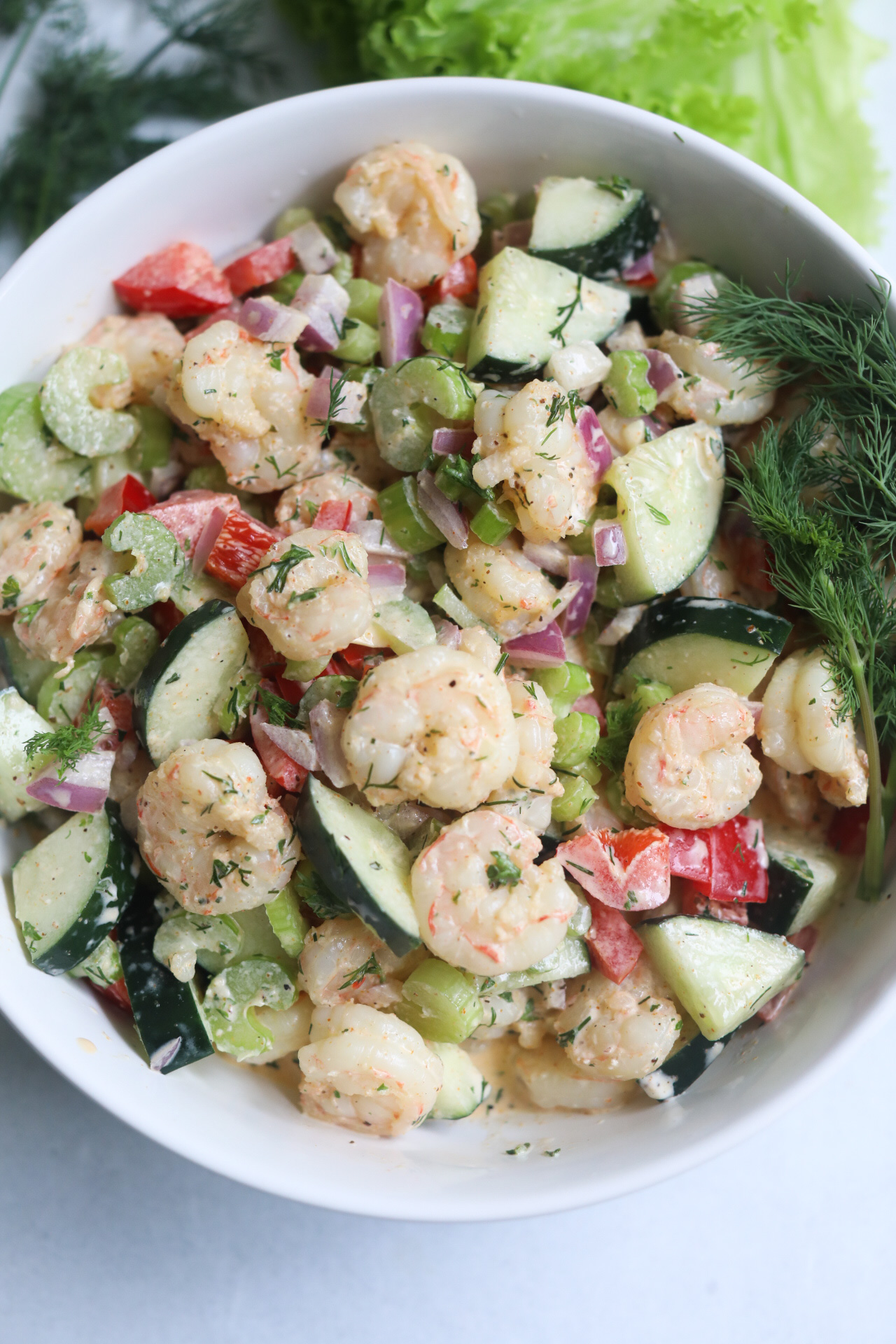 Final recipe of cold shrimp salad plated in a white bowl with fresh dill.