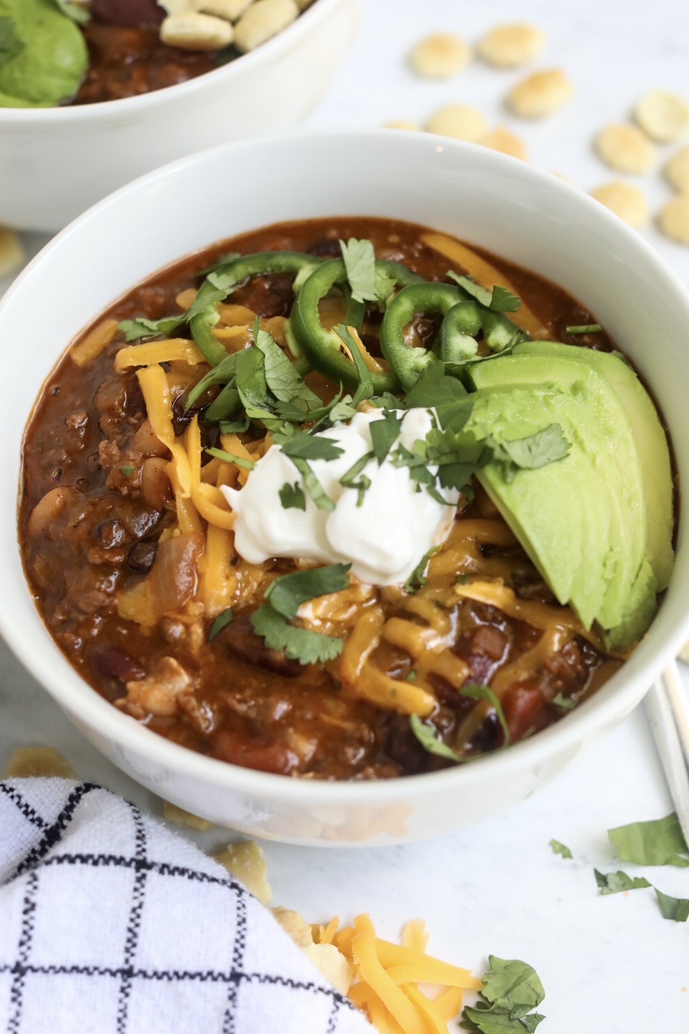 seasoned to taste blog chocolate chili Sweet chili in a white bowl with toppings and decorative white towel added for styling purposes.