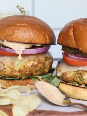 Featured image for tuna burger. Two burgers dressed and stacked with chips added for styling purposes.