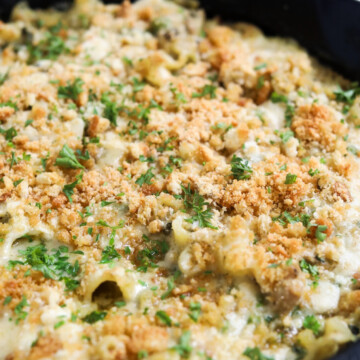 Tuna casserole served in a black cast iron skillet, topped with breadcrumbs and fresh parsley for styling purposes.