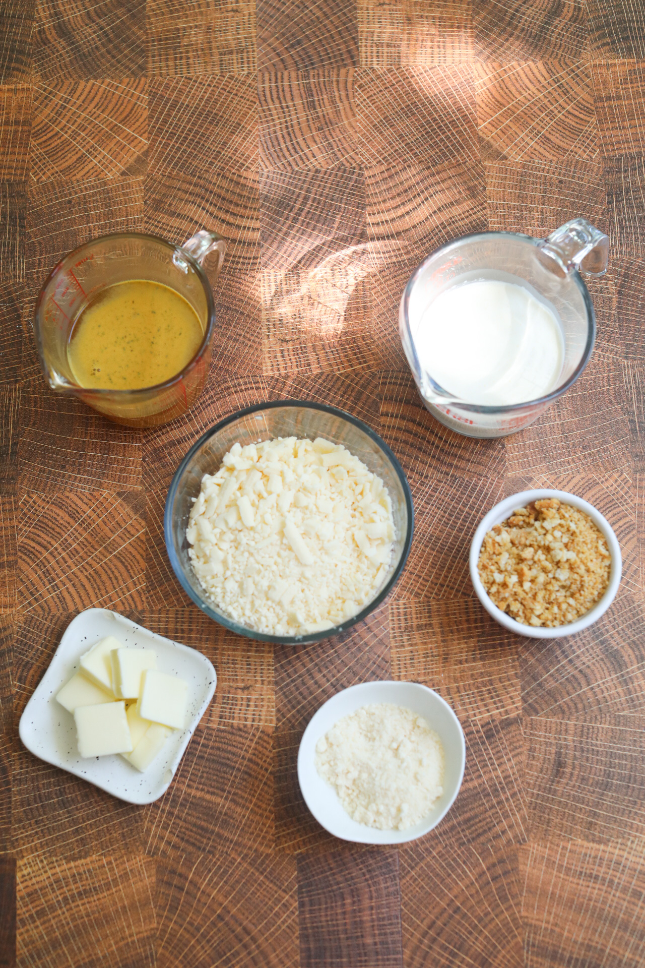 Tuna casserole cream sauce ingredients flay lat. Two glass measuring jars and small plates of cream sauce ingredients.