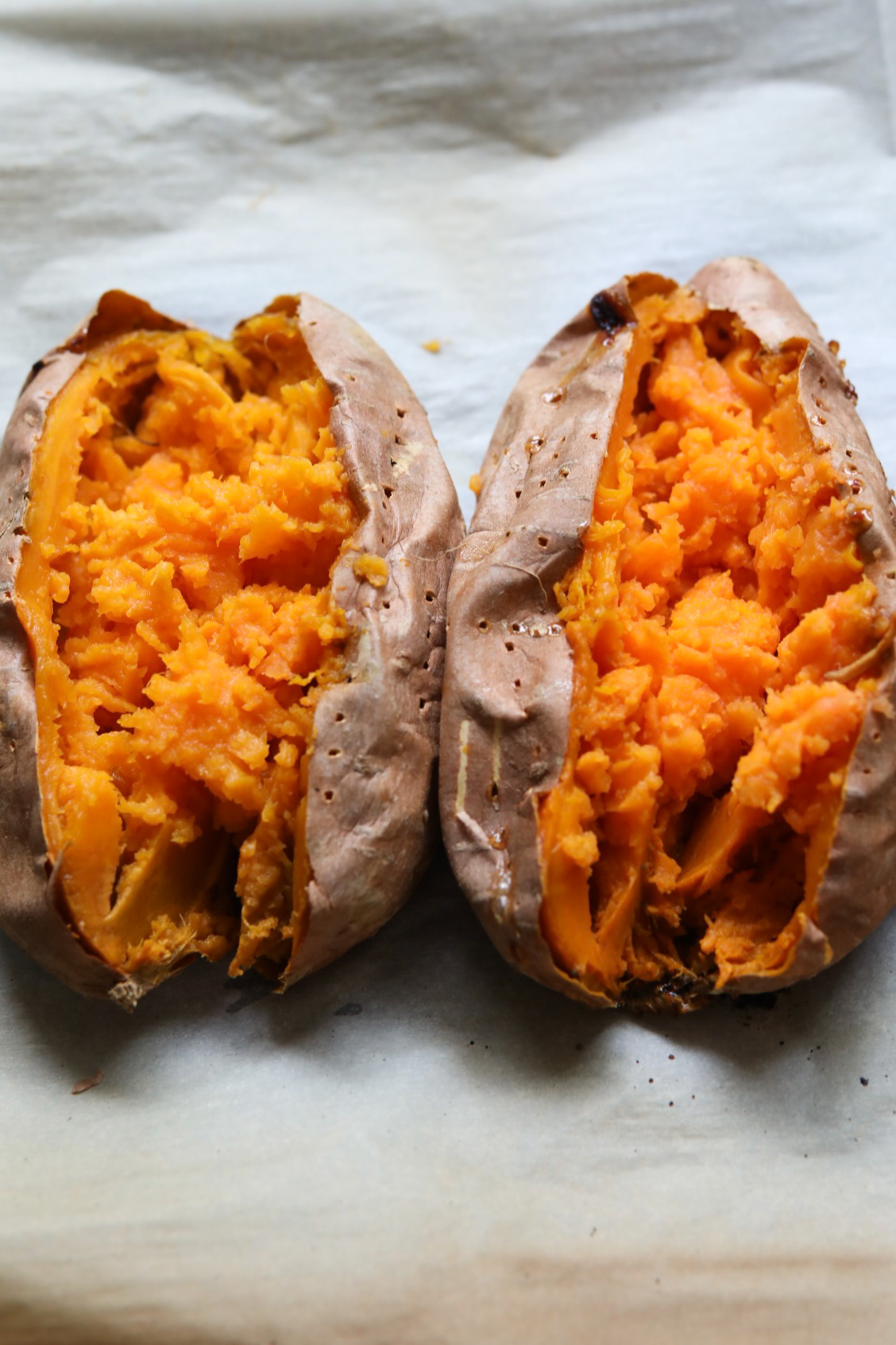 two baked sweet potatoes sliced down the middle to reveal fluffy centers