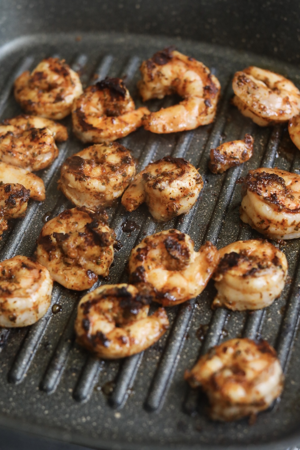 Grilled cajun shrimp in a black grill pan.