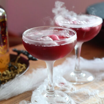 Halloween cocktail with dry ice. Fake spider web is added for styling purposes to show spooky flare with cocktail.