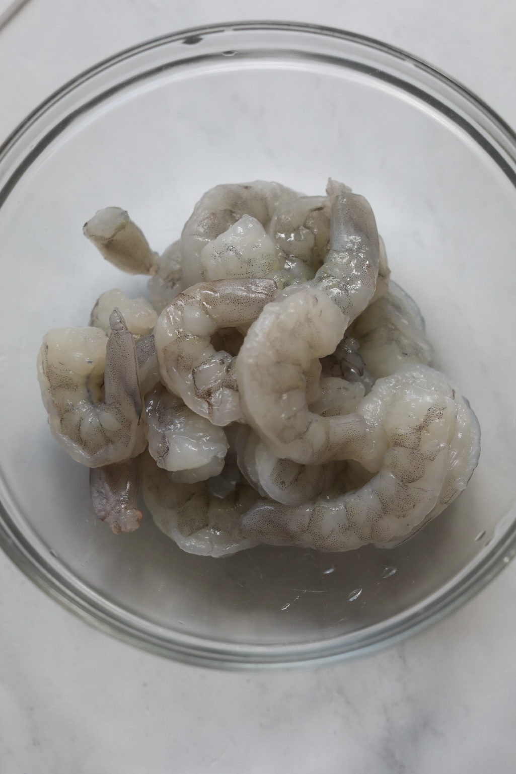 Raw shrimp in a bowl, showing size of shrimp before cooking.