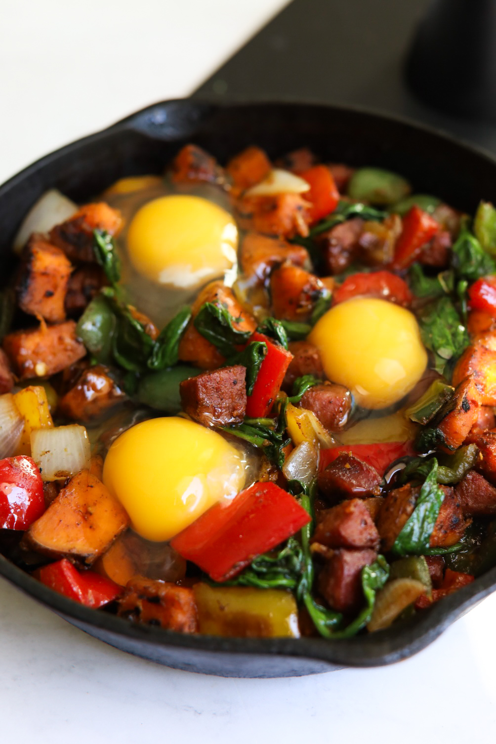 Potato hash with raw eggs in a small black cast iron before baking.