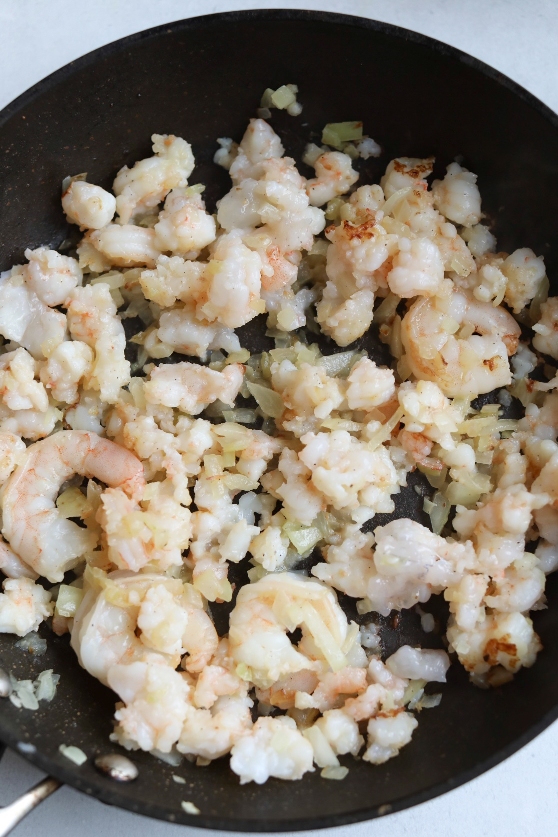shrimp sautéing with onions and garlic in a skillet