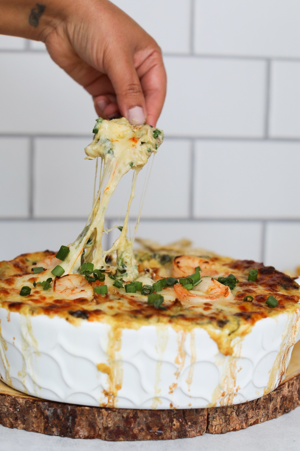 a hand dipping into a dish full of creamy seafood dip