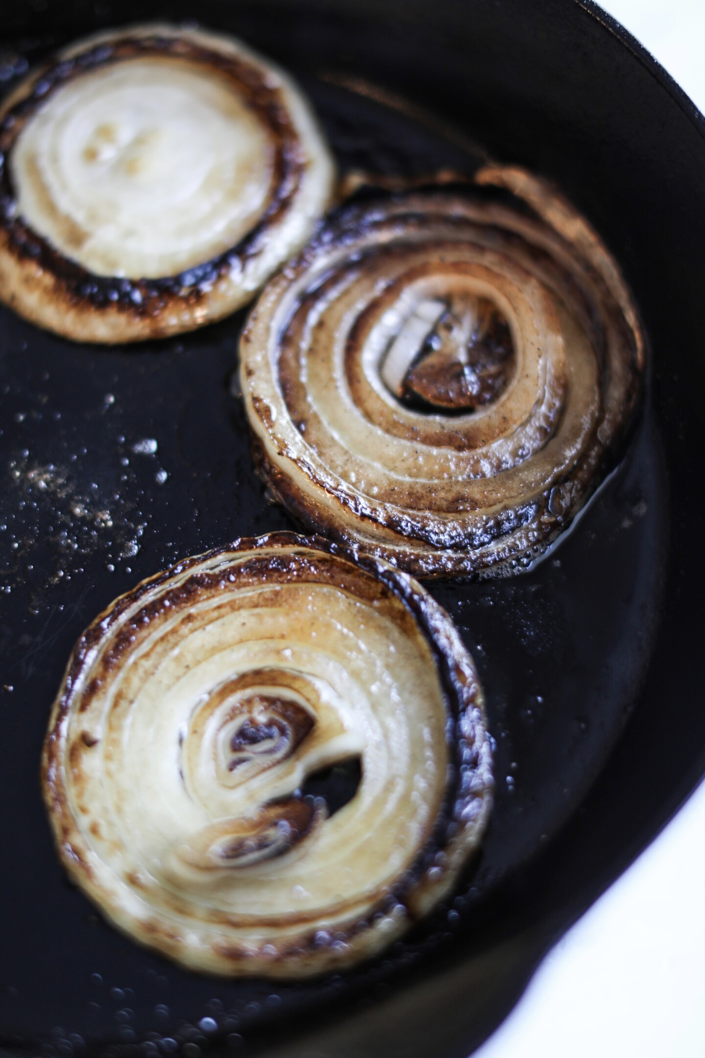 Grilled onion rounds in a black cast iron skillet.