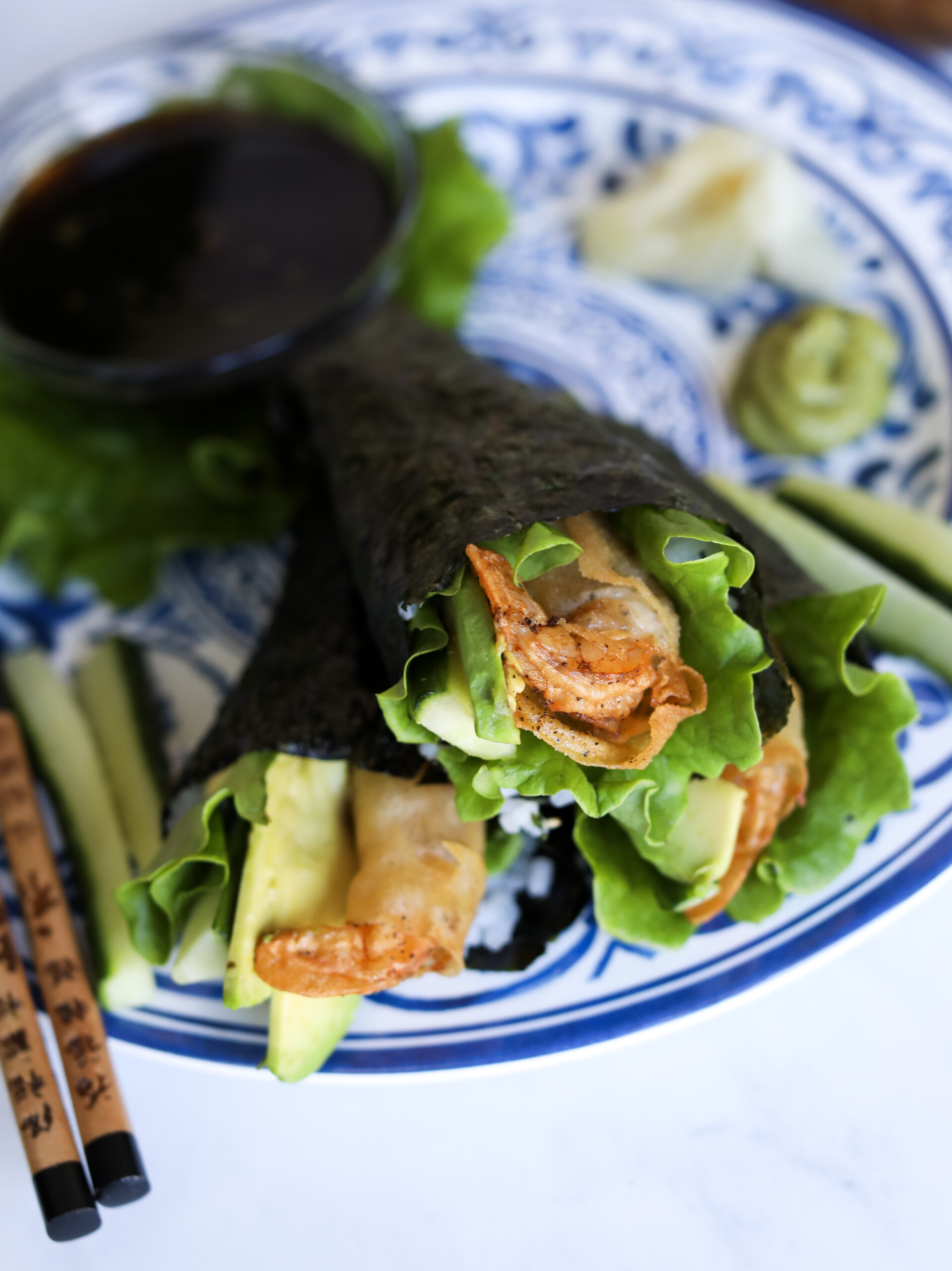 Zoomed image of hand rolls stacked on a blue and white asian style plate.