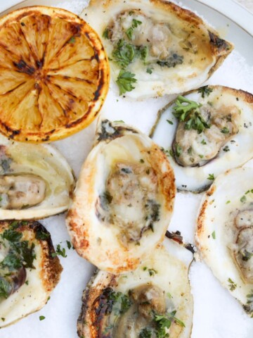plated view of grilled oysters with lemon wedges