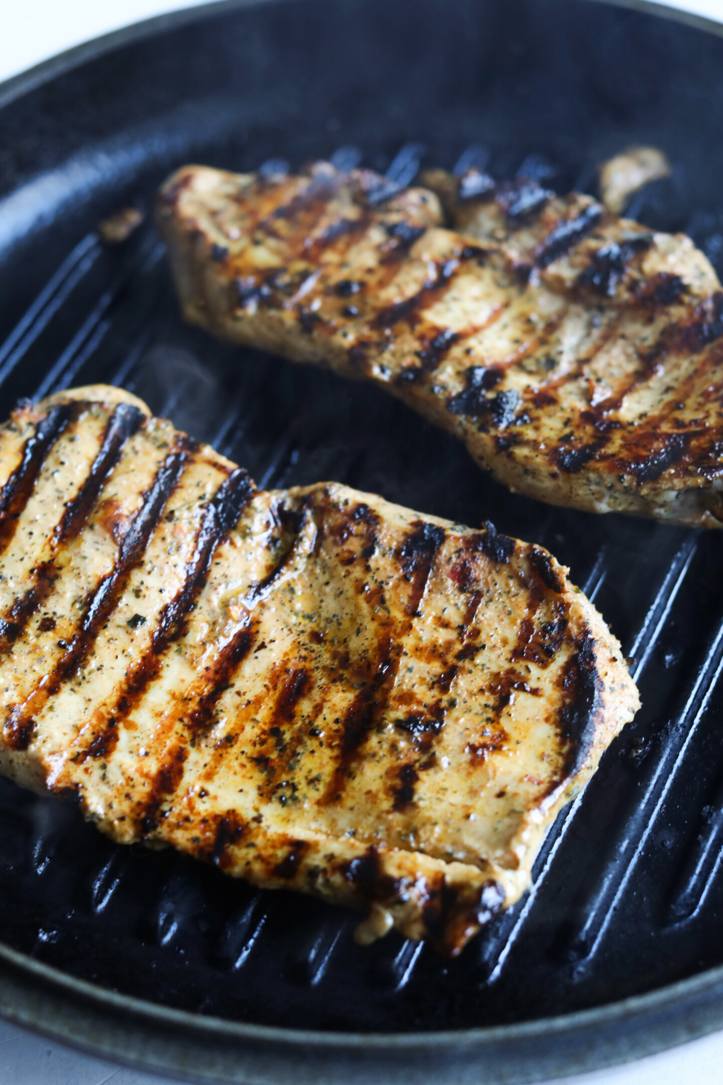 Grilled chicken breasts in black iron skillet.