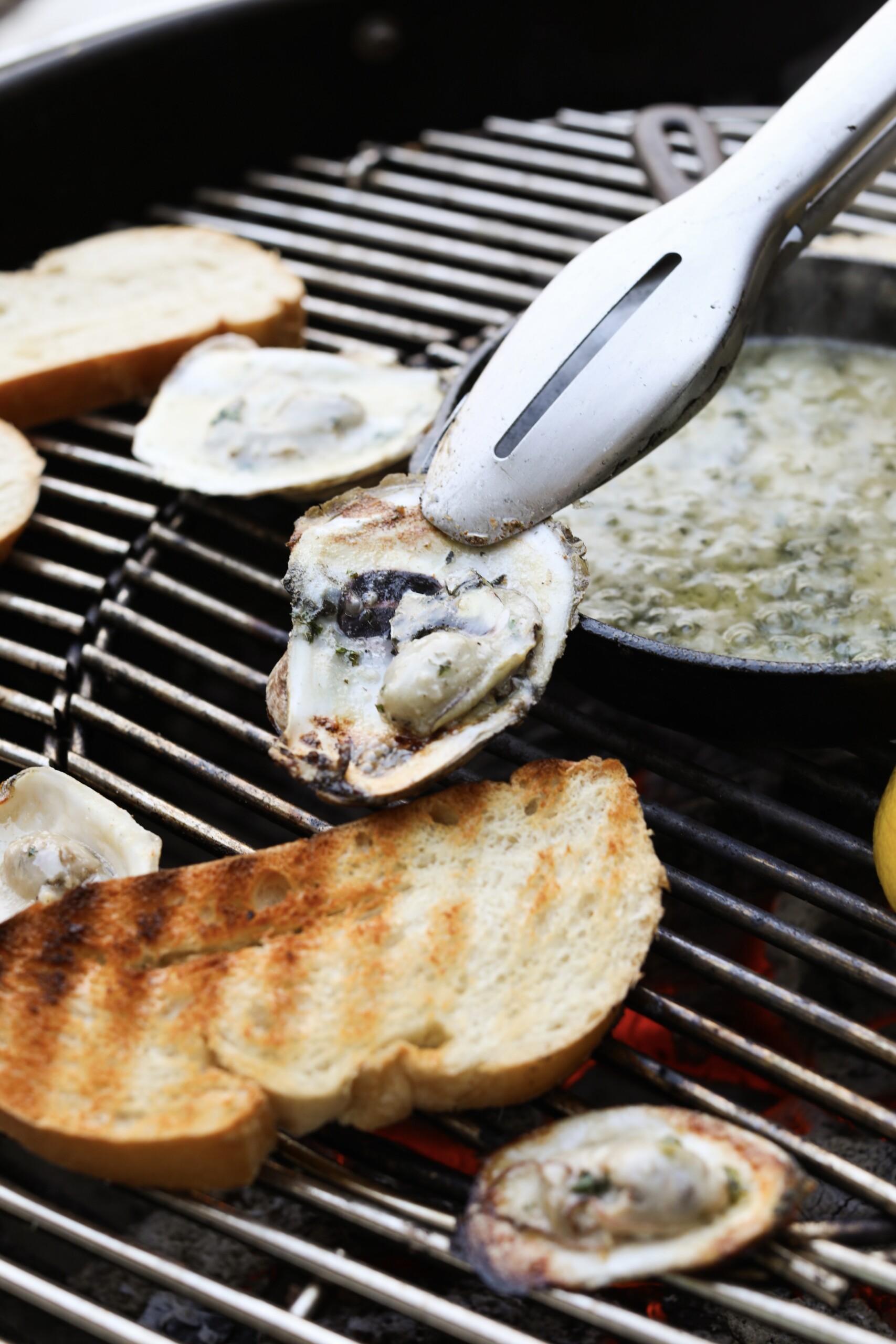 a tong holding an oyster over a grill