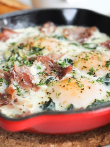 Baked eggs in a red cast iron filled with prosciutto, spinach and shallot.
