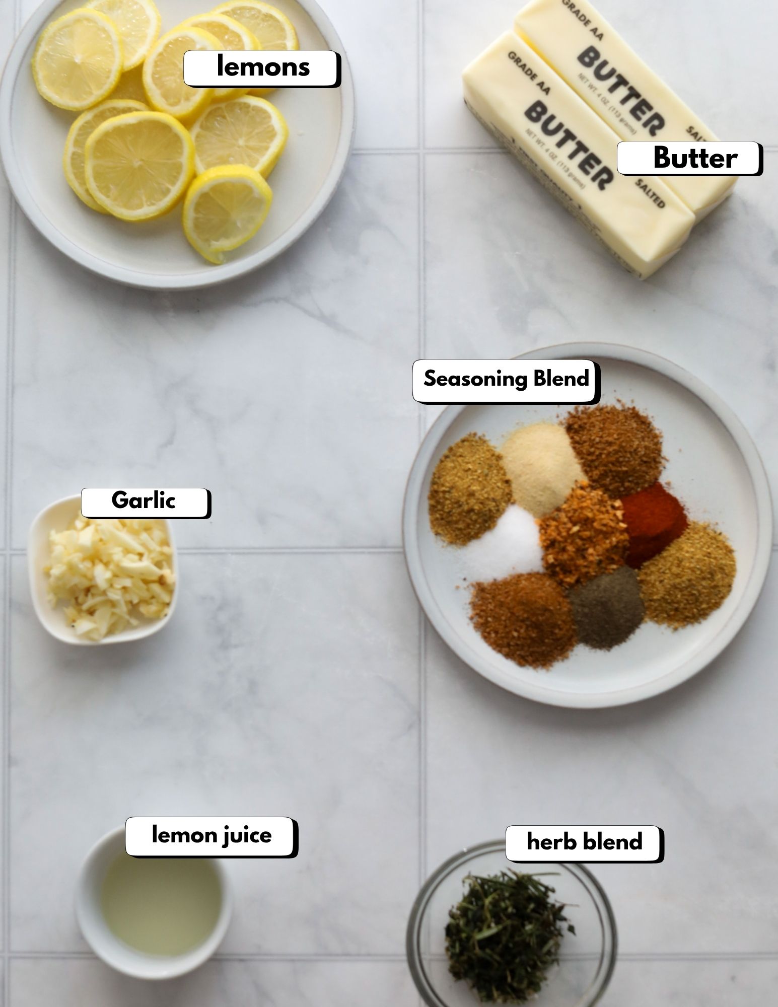 butter rub for roast chicken Overhead image of labeled butter rub ingredients including butter, lemon juice, garlic, seasoning blend, herb blend, and lemon slices.