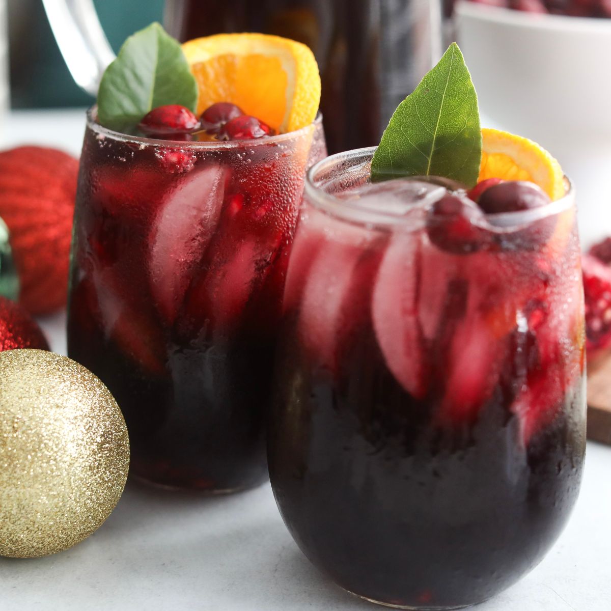 Christmas punch Two glasses of Christmas Punch with ice, orange slices, cranberries, and greenery, set on a holiday table with red and gold ornaments.